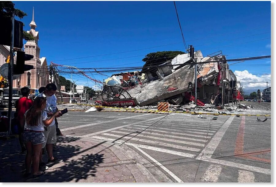 Click to enlarge People stand near a collapsed building after a magnitude 7.8 quake in General Santos, Philippines, June 8, 2026.