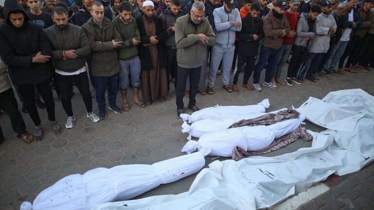 Palestinians pray by shrouded bodies of people killed following Israeli bombardment in the Gaza Strip.