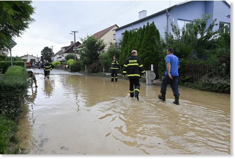 Members of the Czech emergency services walk through a flooded street following heavy rains in the Czech Republic's east.