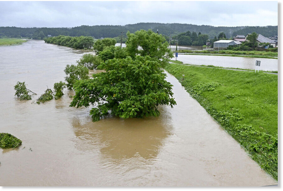 Photo taken in the morning on July 25, 2024, shows a river (L) that has burst its banks in Yurihonjo, Akita