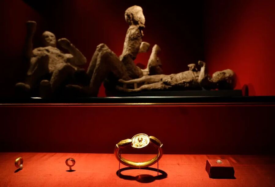 Jewelry found in the ruins of a house in Pompeii, with casts of four victims in the background, on exhibit at the British Museum in central London.