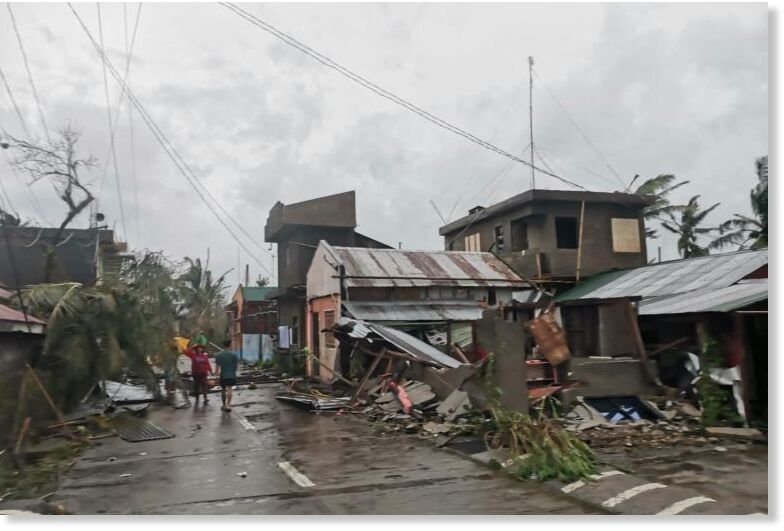 Residents walk past destroyed houses in Panganiban town in the islan